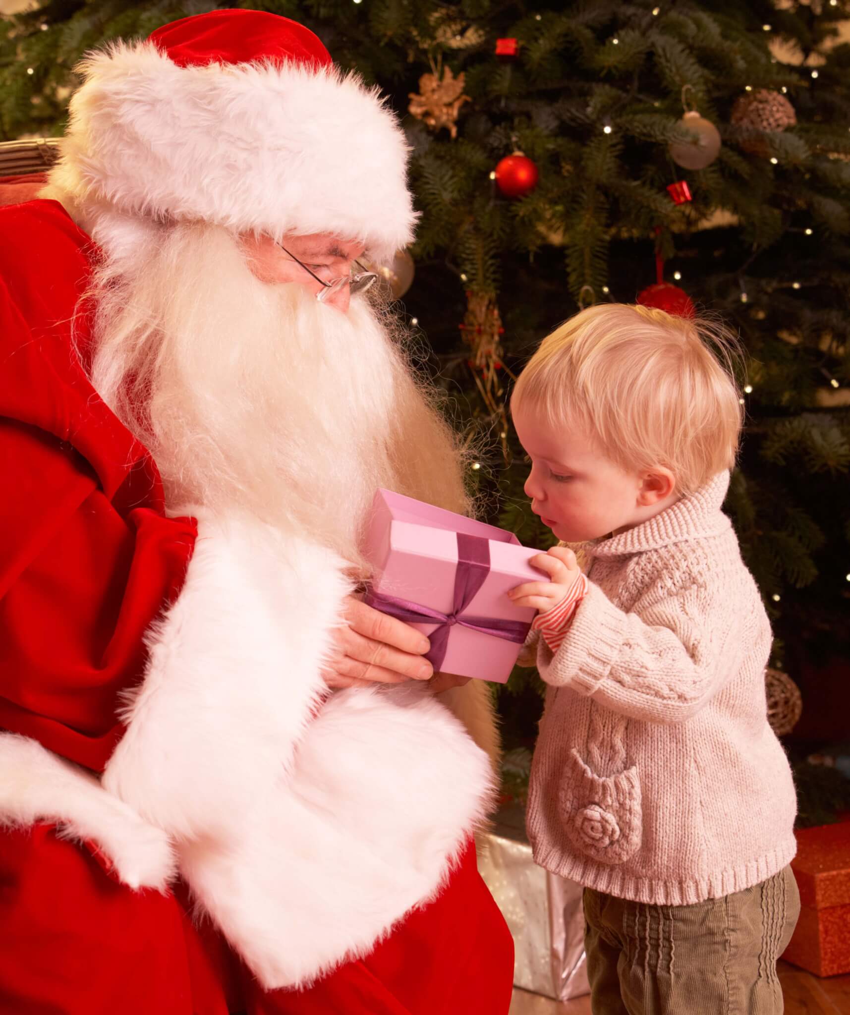 Santa Claus Giving Gift To Boy In Front Of Christmas Tree